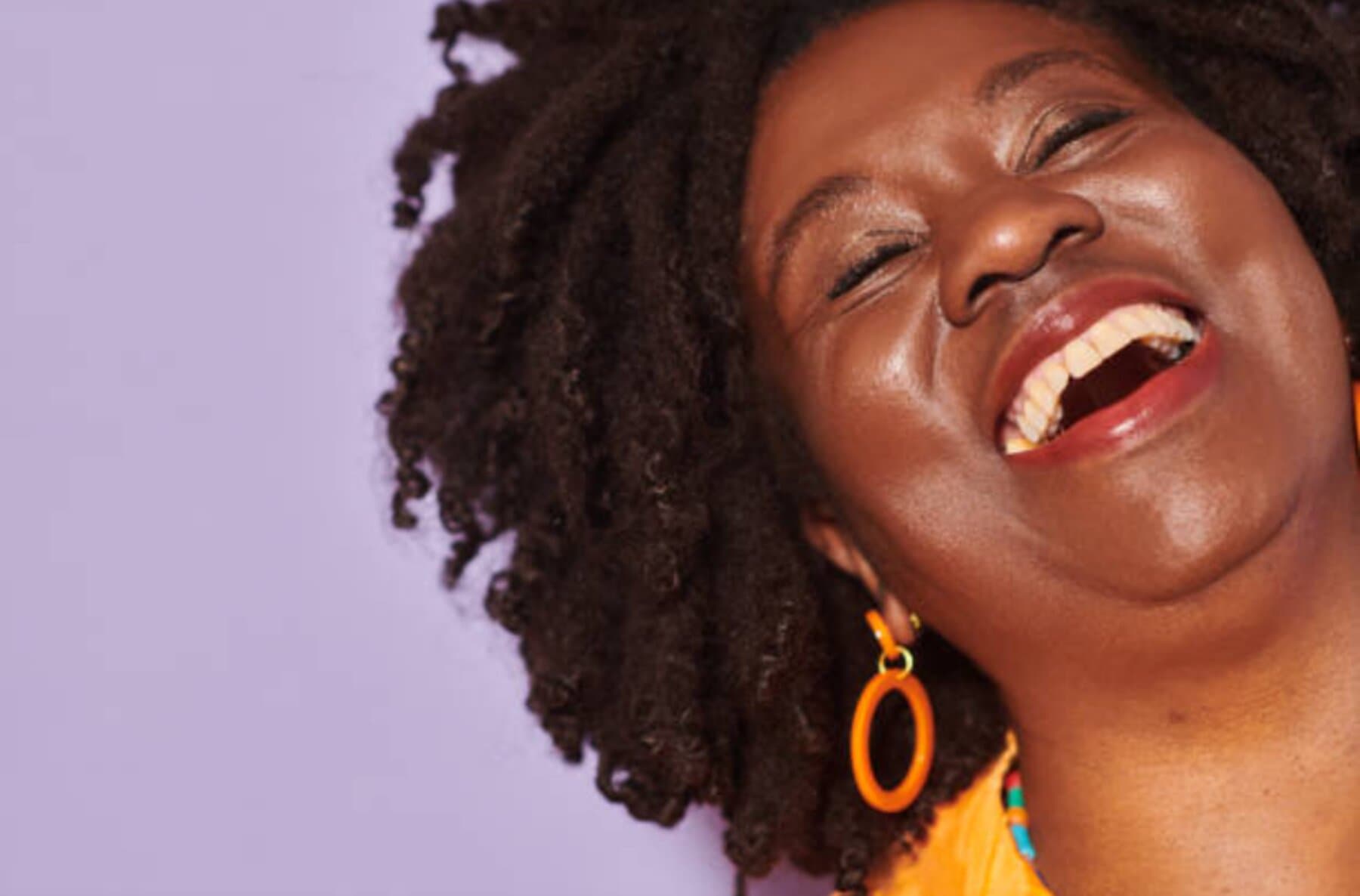 Black woman laughing with pure joy, head back, eyes closed — uninhibited and radiant