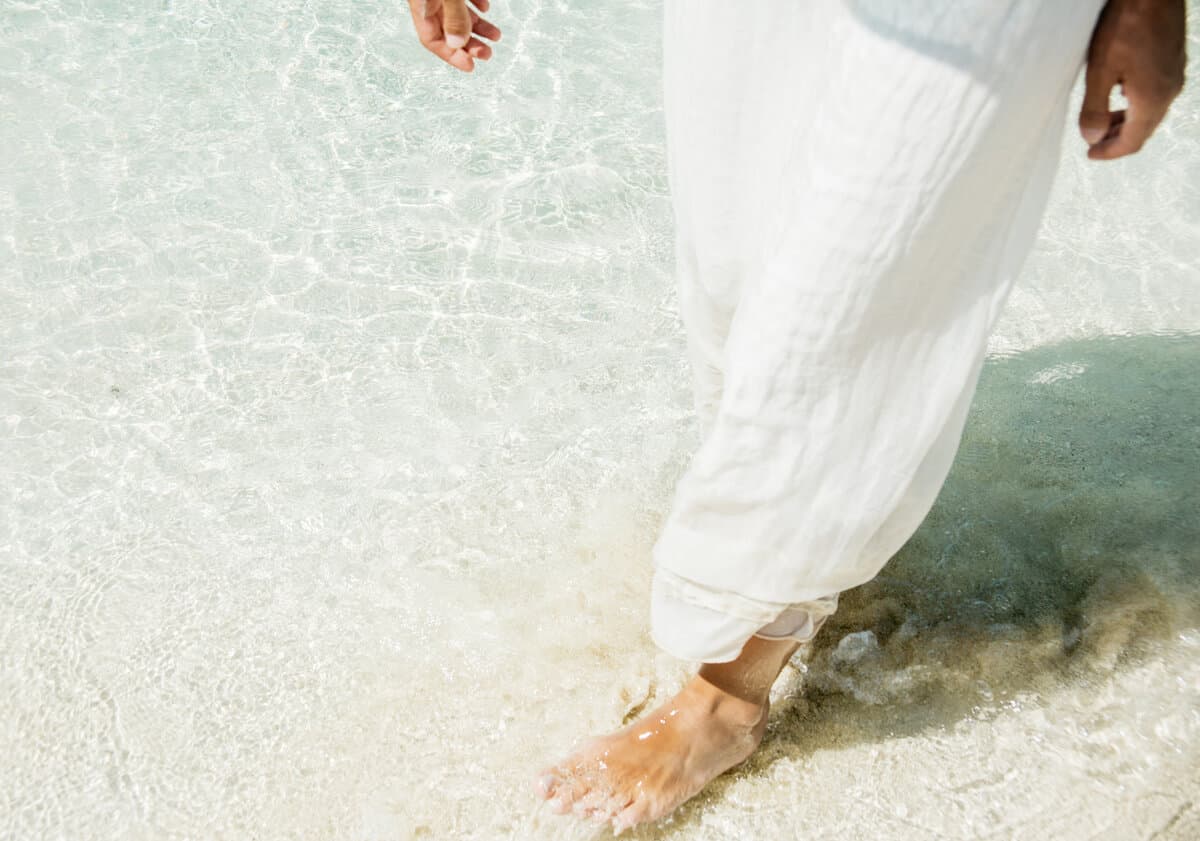 Woman walking barefoot at the water's edge, solitary and reflective at golden hour