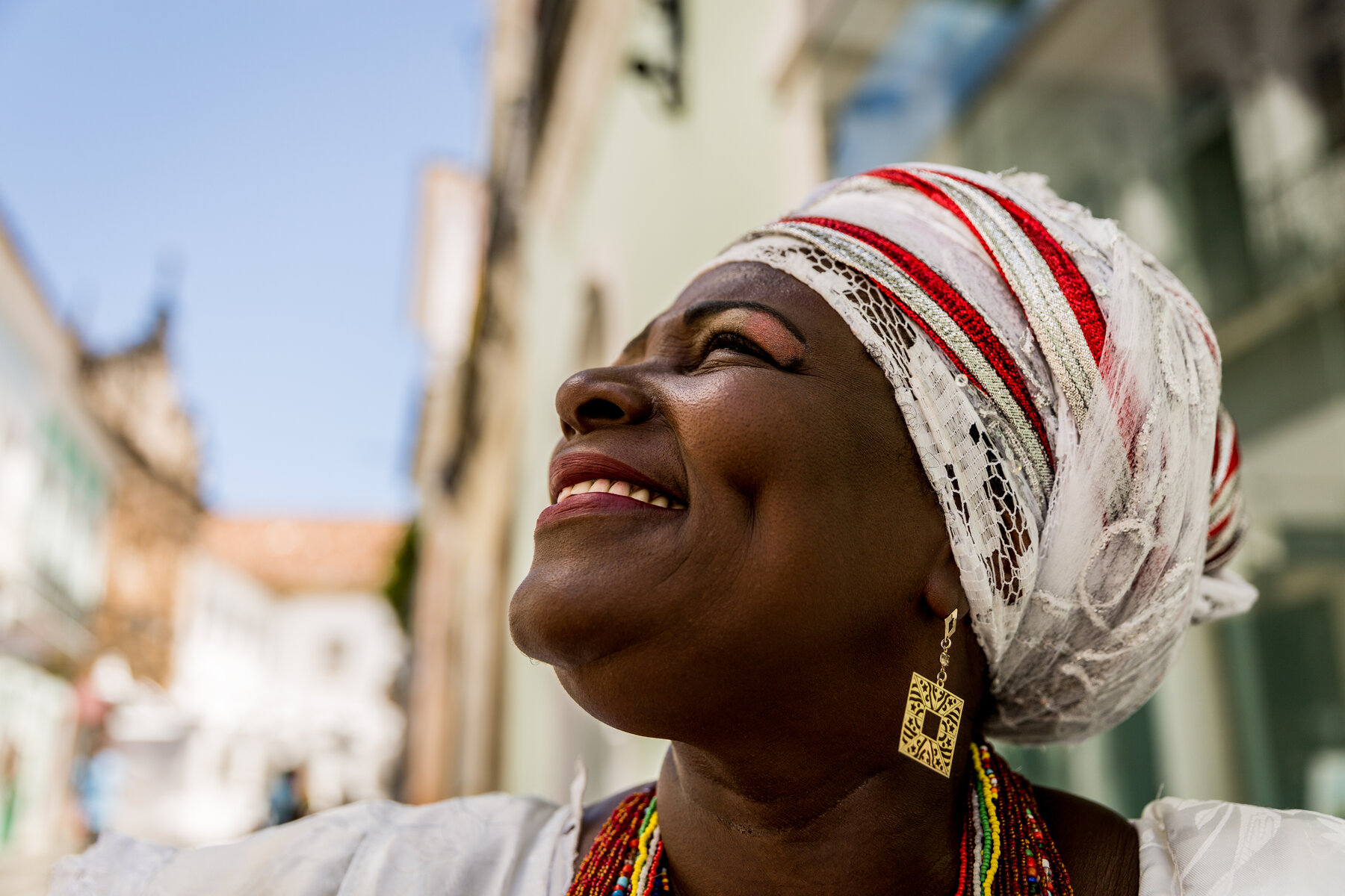 Bahian woman in golden yellow headwrap and traditional dress, gazing upward — Salvador, Bahia