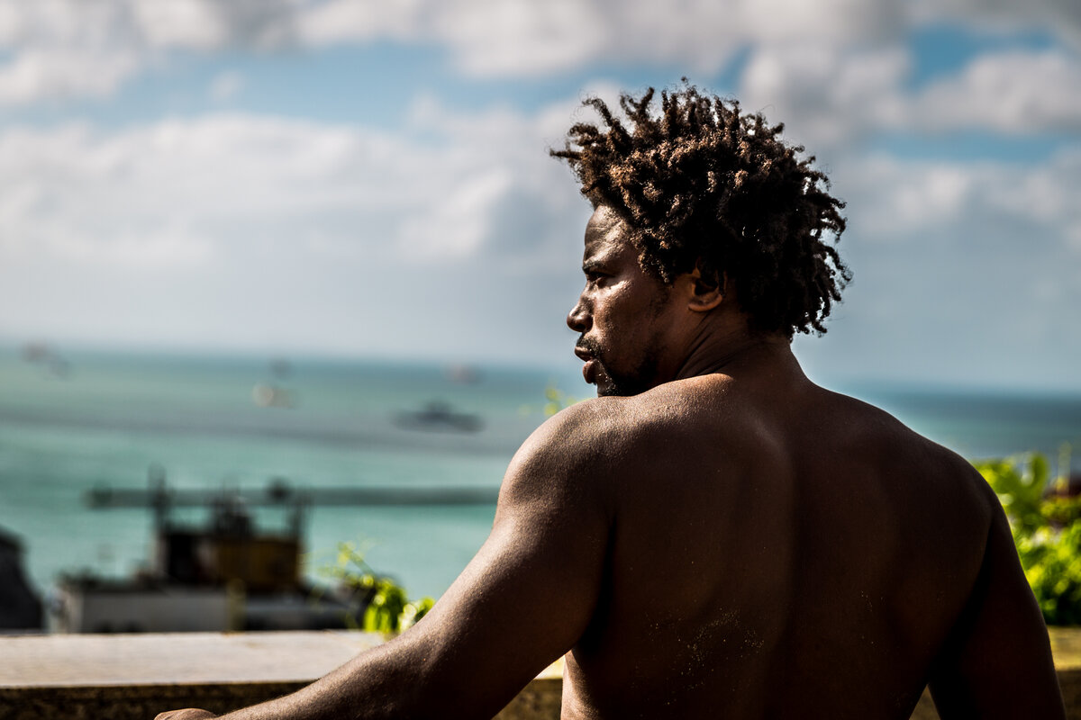 Man with locs gazing out over the turquoise bay of Salvador, Bahia